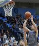 NYU student throwing basketball into hoop, about to score a point