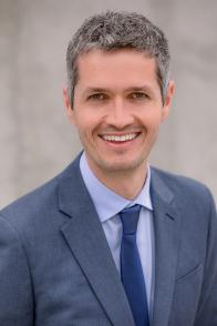 Man wearing blue blazer and tie smiling at the camera